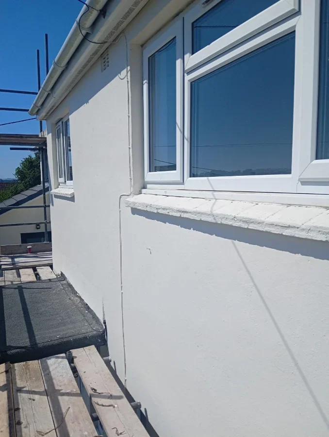 After refubishment image of a freshly rendered and painted white exterior wall with new sills on a Falmouth property