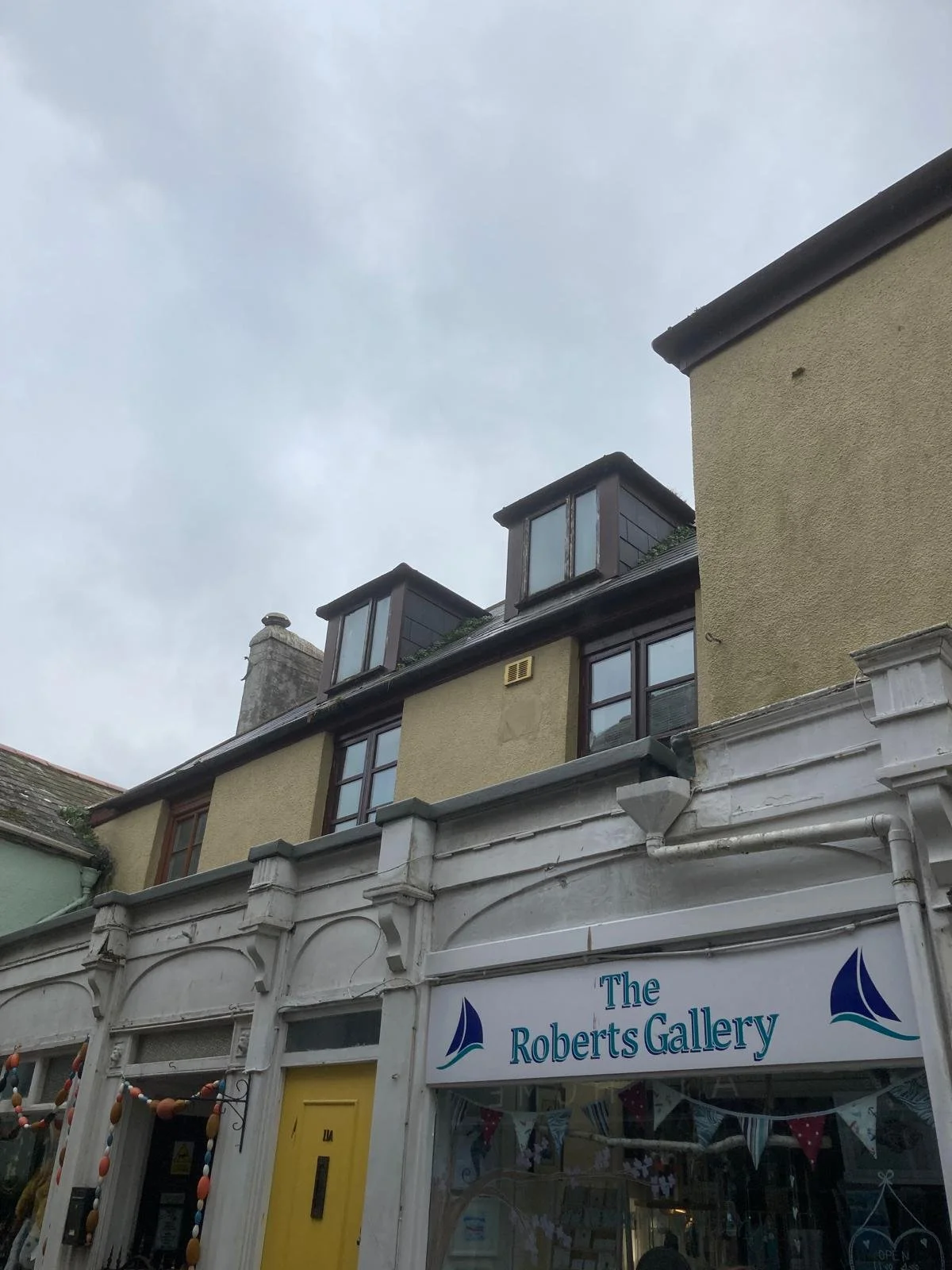 View of a building with dormer windows on the rooftop and a storefront below that reads 'The Roberts Gallery'.