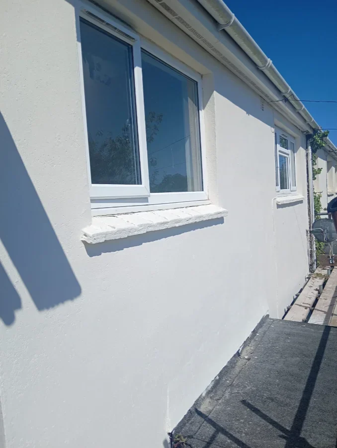Freshly rendered and painted white exterior wall with new sills on a Falmouth property