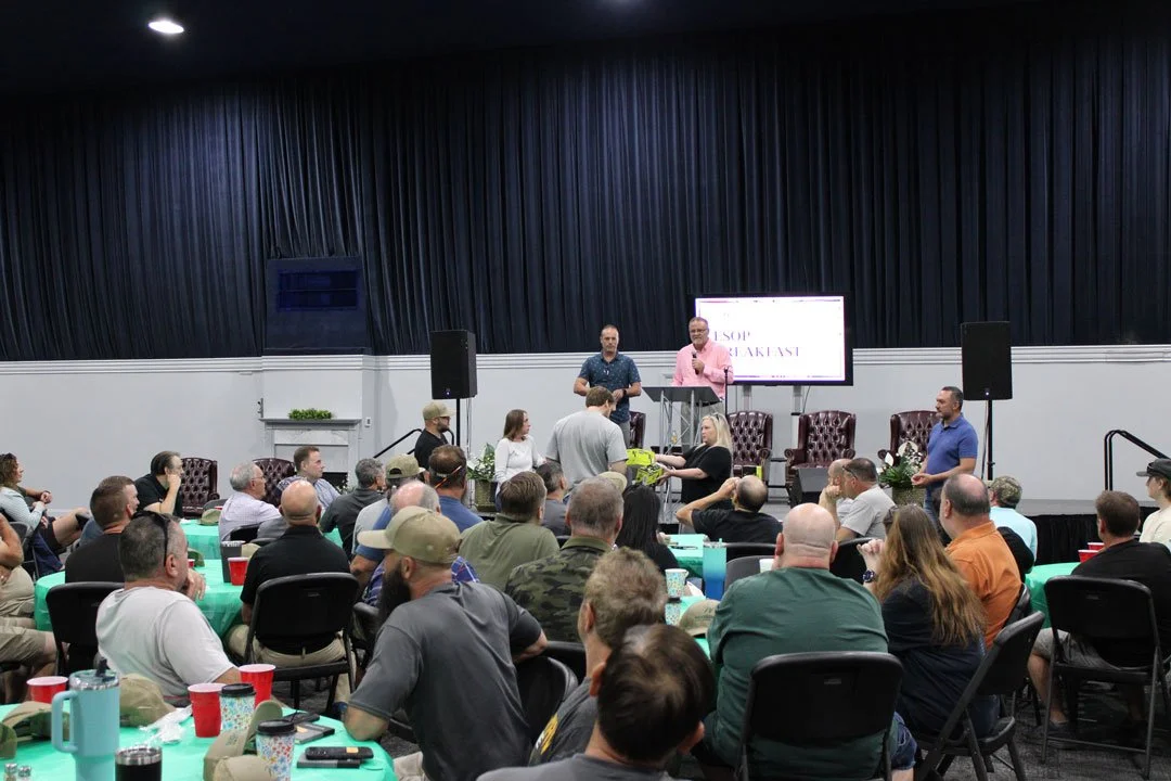 Woodsman employee-owners gather for the company's annual ESOP Breakfast, listening to speakers and participating in a raffle while seated around tables in a large event space.