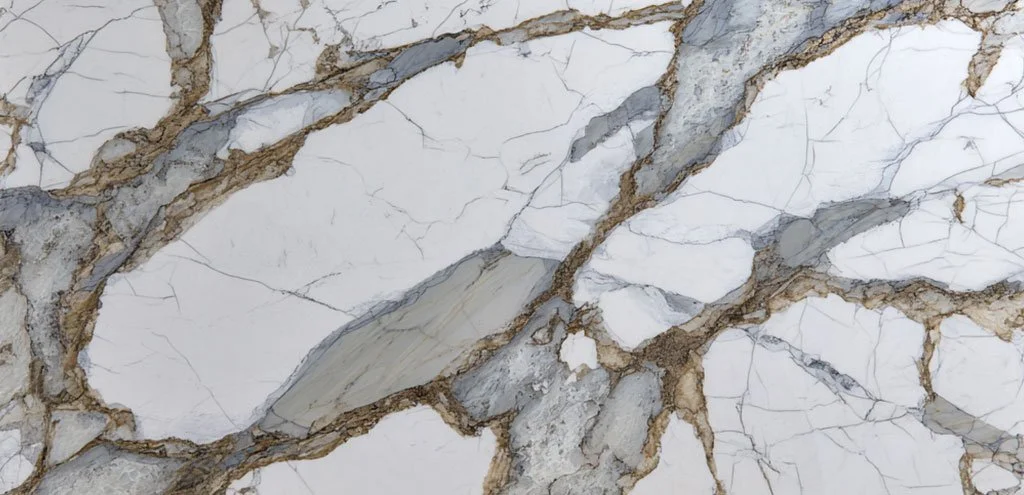 Close-up of quartz surface with a white base, dramatic gray veining, and warm gold accents running through the pattern.