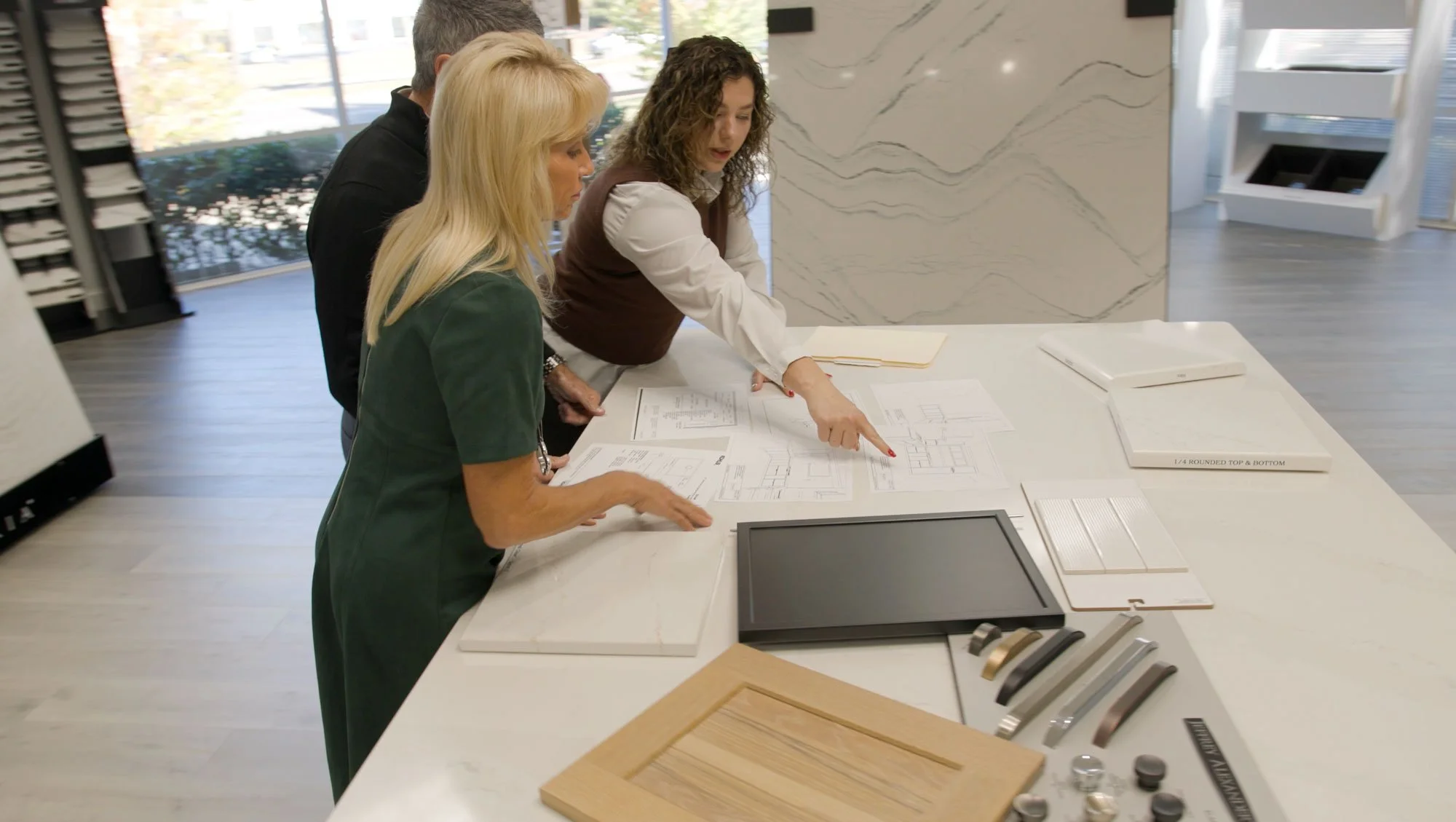 A designer showing samples to two customers in the showroom.
