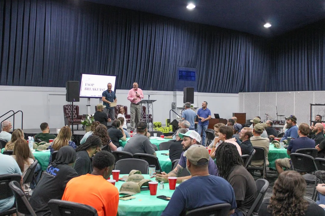Woodsman employee-owners gather for the annual ESOP Breakfast, participating in a raffle and company meeting while seated around tables in a large event space.