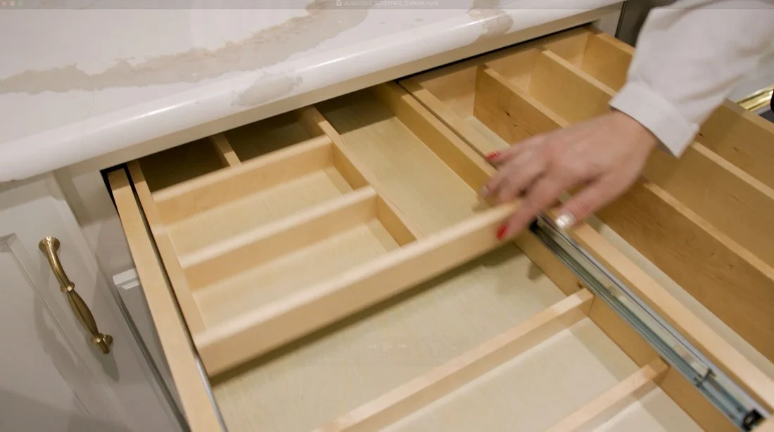 Kitchen drawer with a custom sliding wood organizer, demonstrating adjustable utensil storage and divided compartments for efficient kitchen organization.