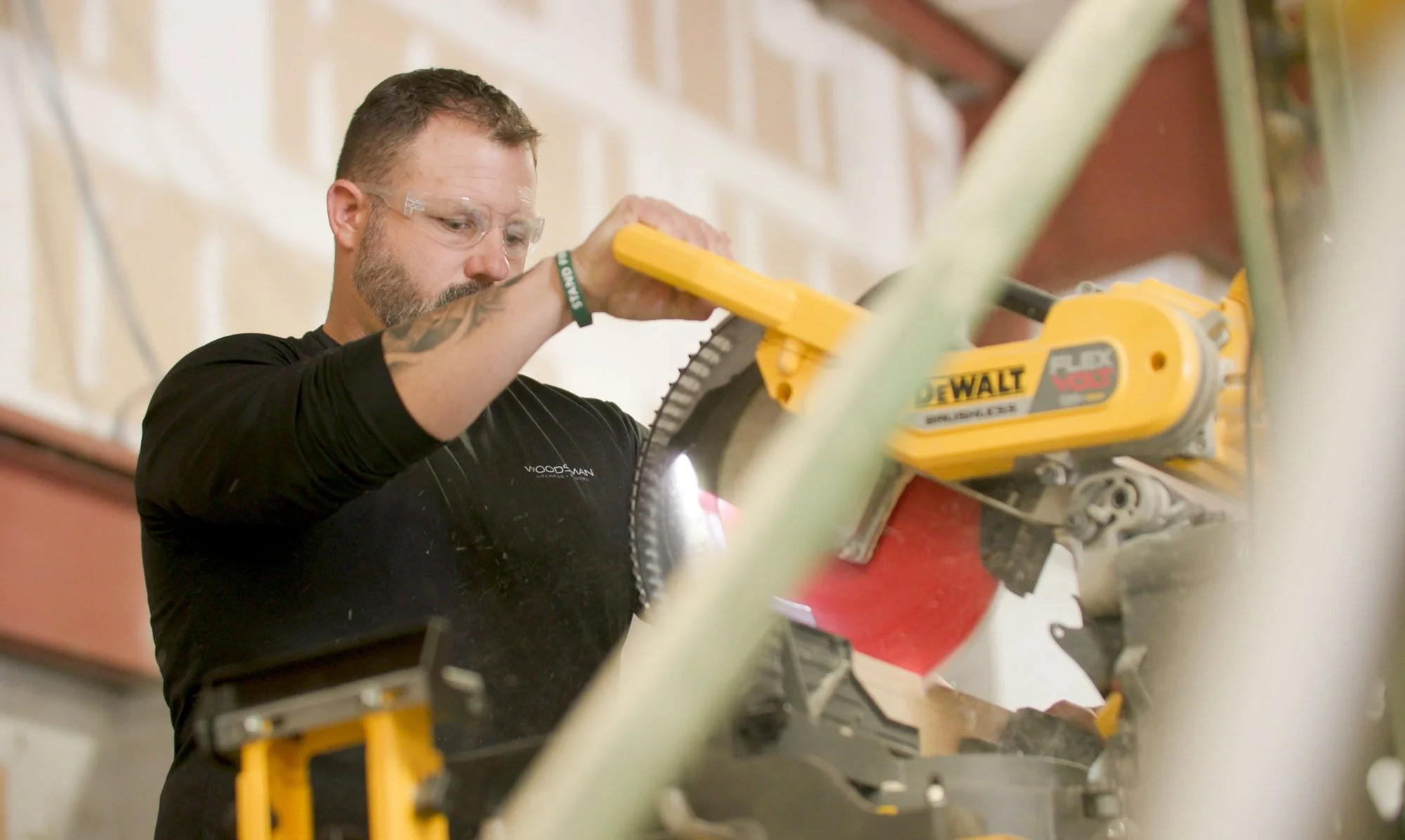 A man using a miter saw to cut a plank of wood.