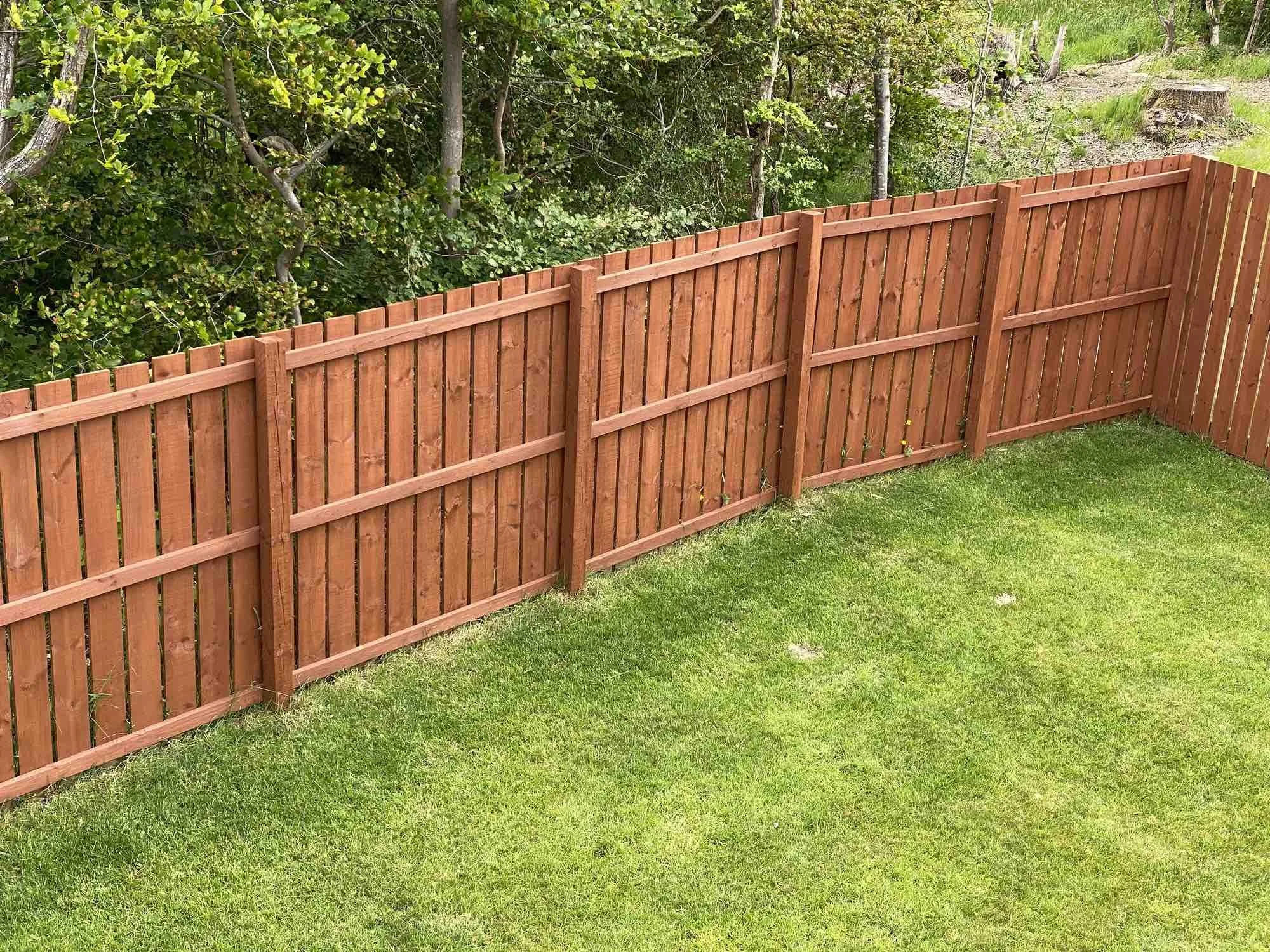 Wooden fence with green grass and trees in the background