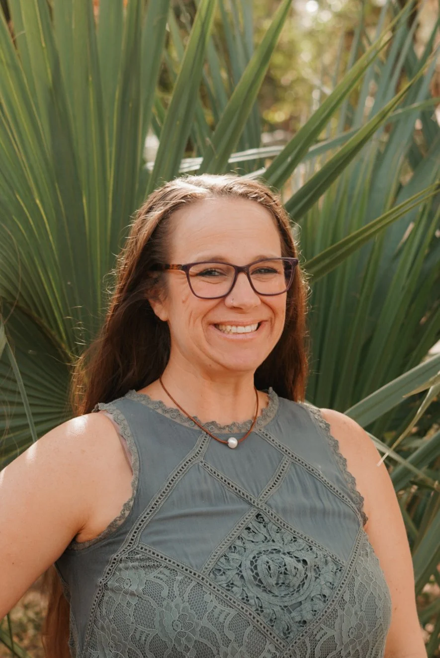 Massage Therapist, Craniosacral Therapist Megan Scott, LMT, Growing Green Families with grey tanktop, smiling, brunette hair, in front of green foliage