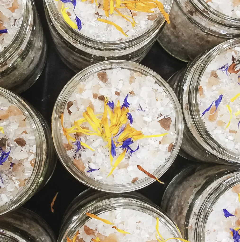 A jar filled with coarse sea salt and colorful flowers, creating a decorative and aromatic display.