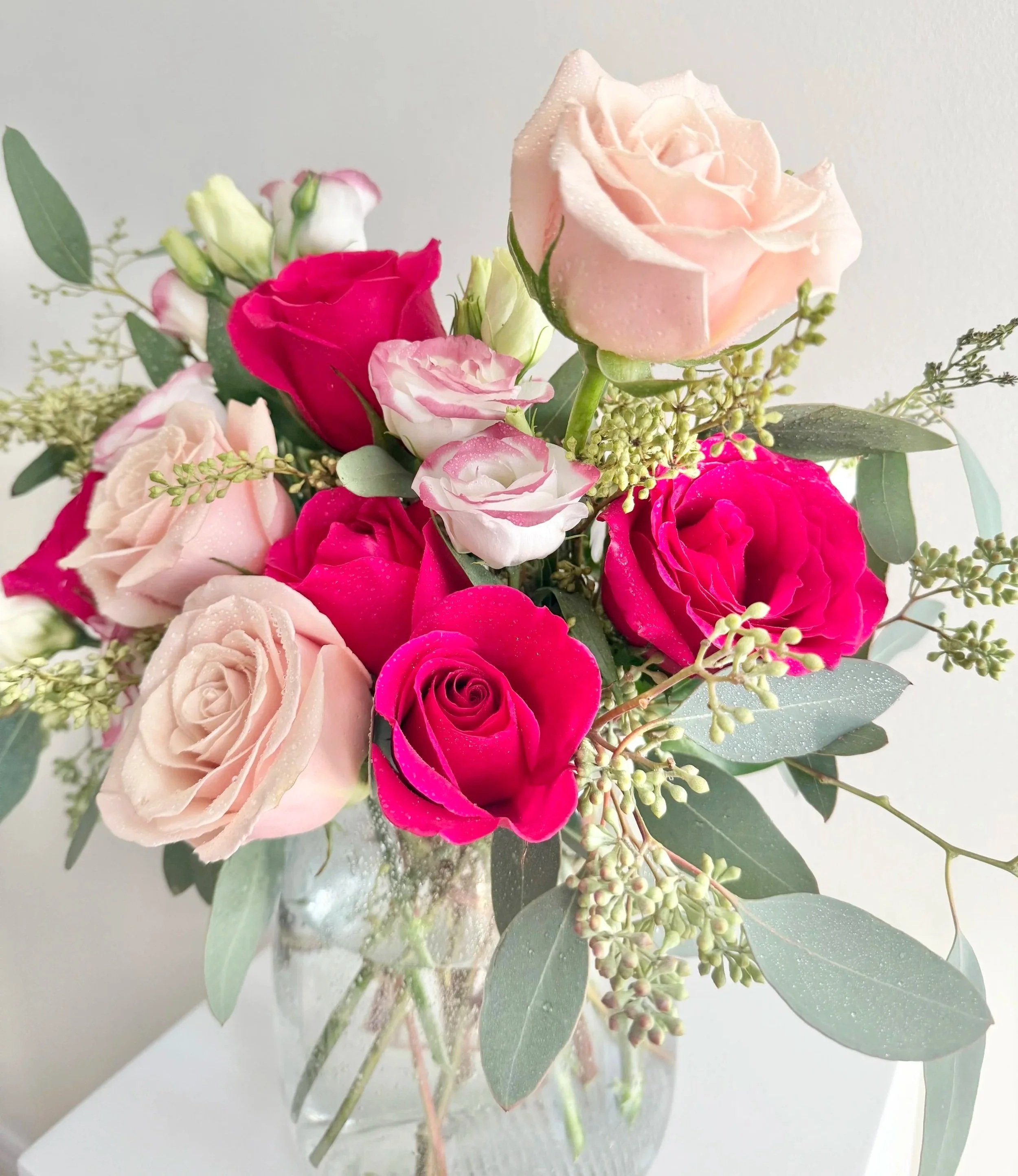 A decorative vase brimming with pink and red roses, highlighting their rich colors and natural beauty.