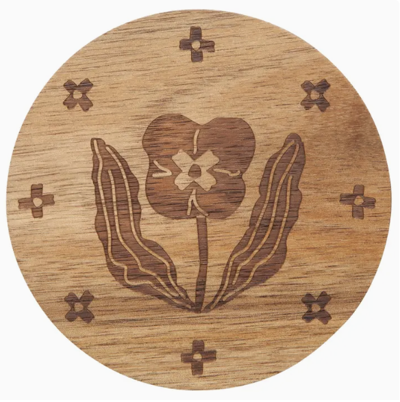 A wooden coaster featuring an intricate flower design carved into its surface.