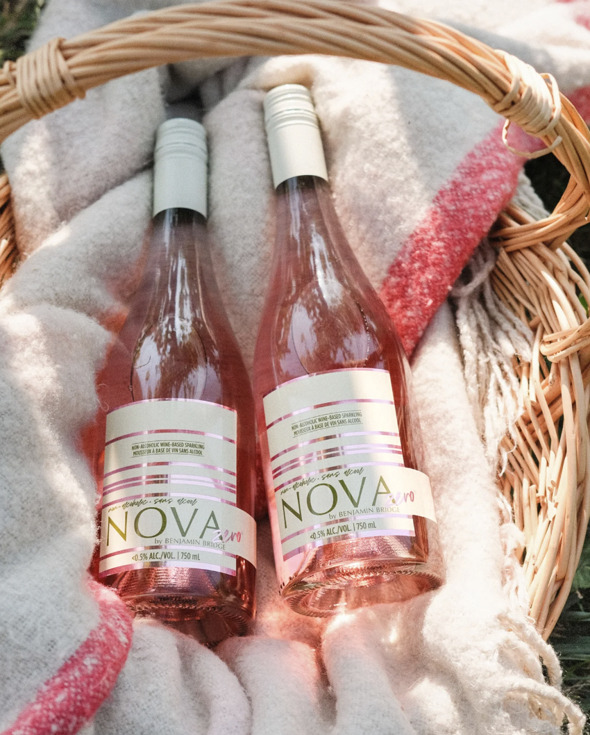 Two bottles of Nova rosé wine nestled in a woven basket, showcasing a charming and elegant presentation.