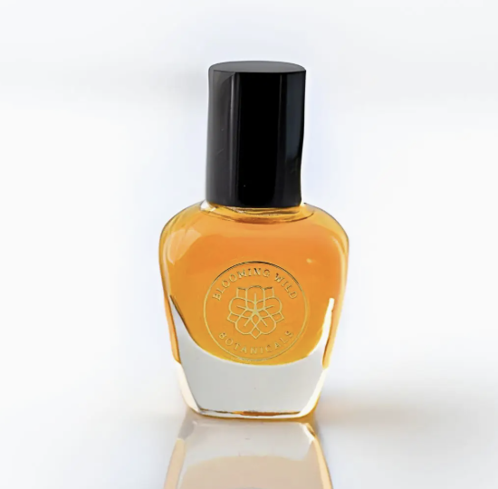 A clear bottle of perfume sits elegantly on a smooth white surface, reflecting light softly.
