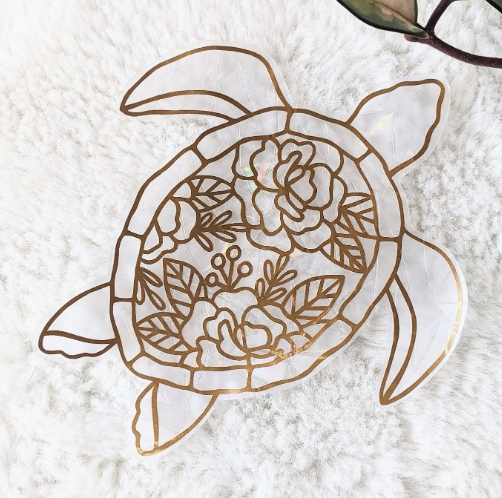 A white turtle adorned with delicate gold leaf accents on its shell.