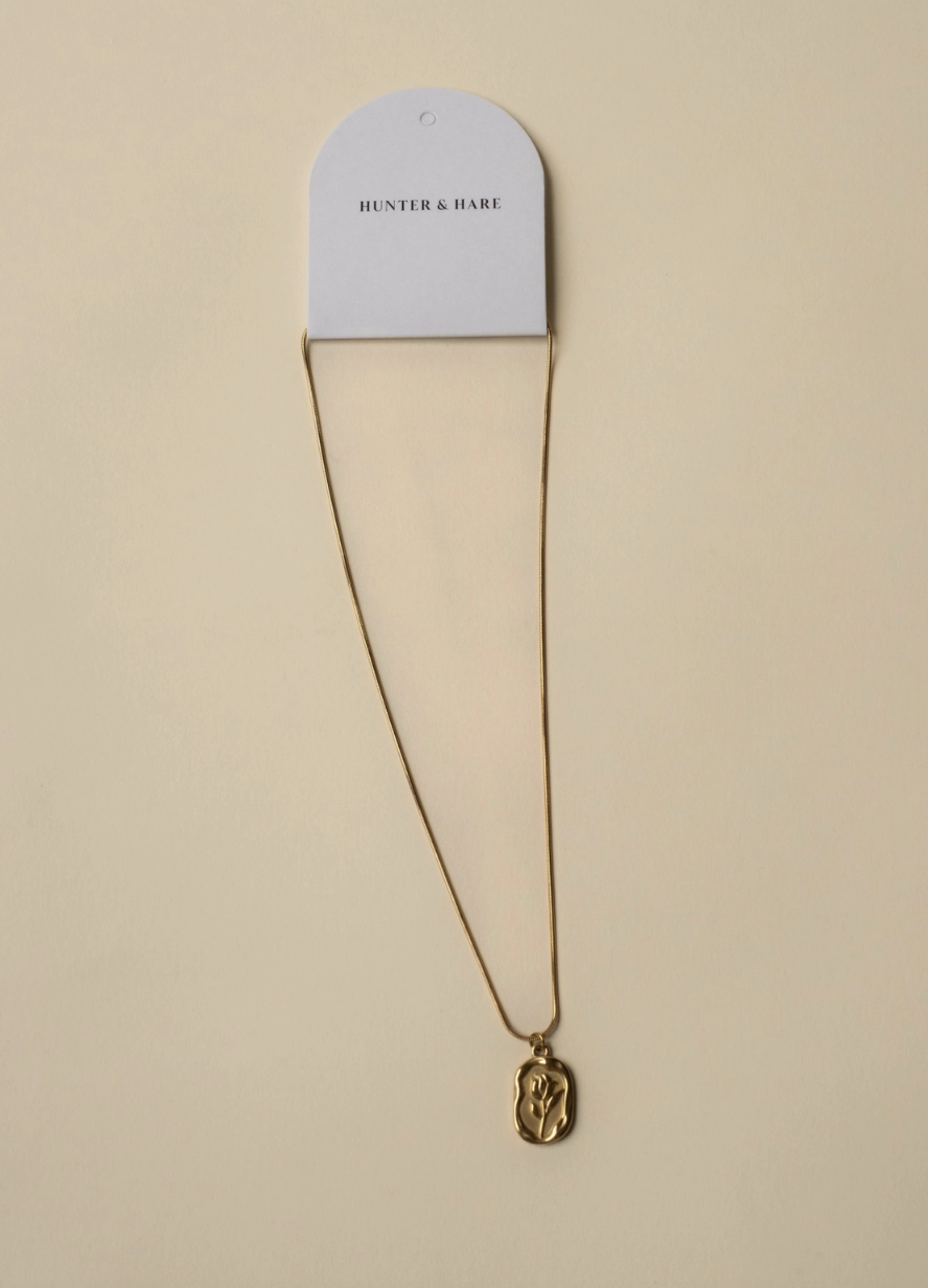 A white and gold necklace suspended from a chain, showcasing its intricate design and shimmering details.