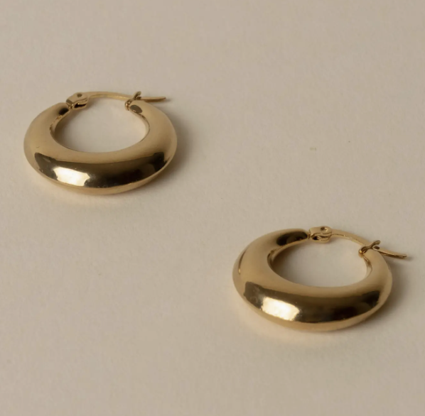Two silver hoop earrings resting on a white surface, showcasing their shiny finish and circular design.