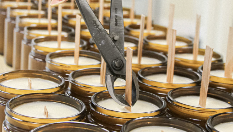 A person using scissors to cut candles, focusing on the precise action of trimming the wax.
