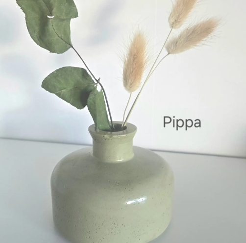 A white vase filled with a lush green plant, showcasing a simple and elegant design.