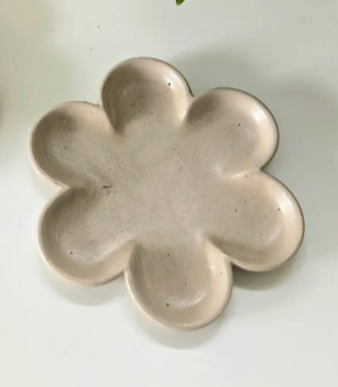 A decorative plate shaped like a flower, adorned with two small wooden studs positioned in the center.
