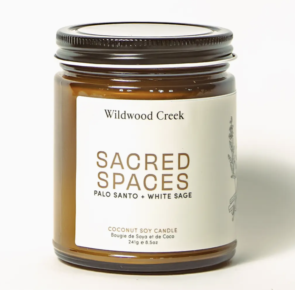 Soy candle labeled "Wildwood Creek Sacred Spaces," featuring a serene design and earthy colors, evoking tranquility.