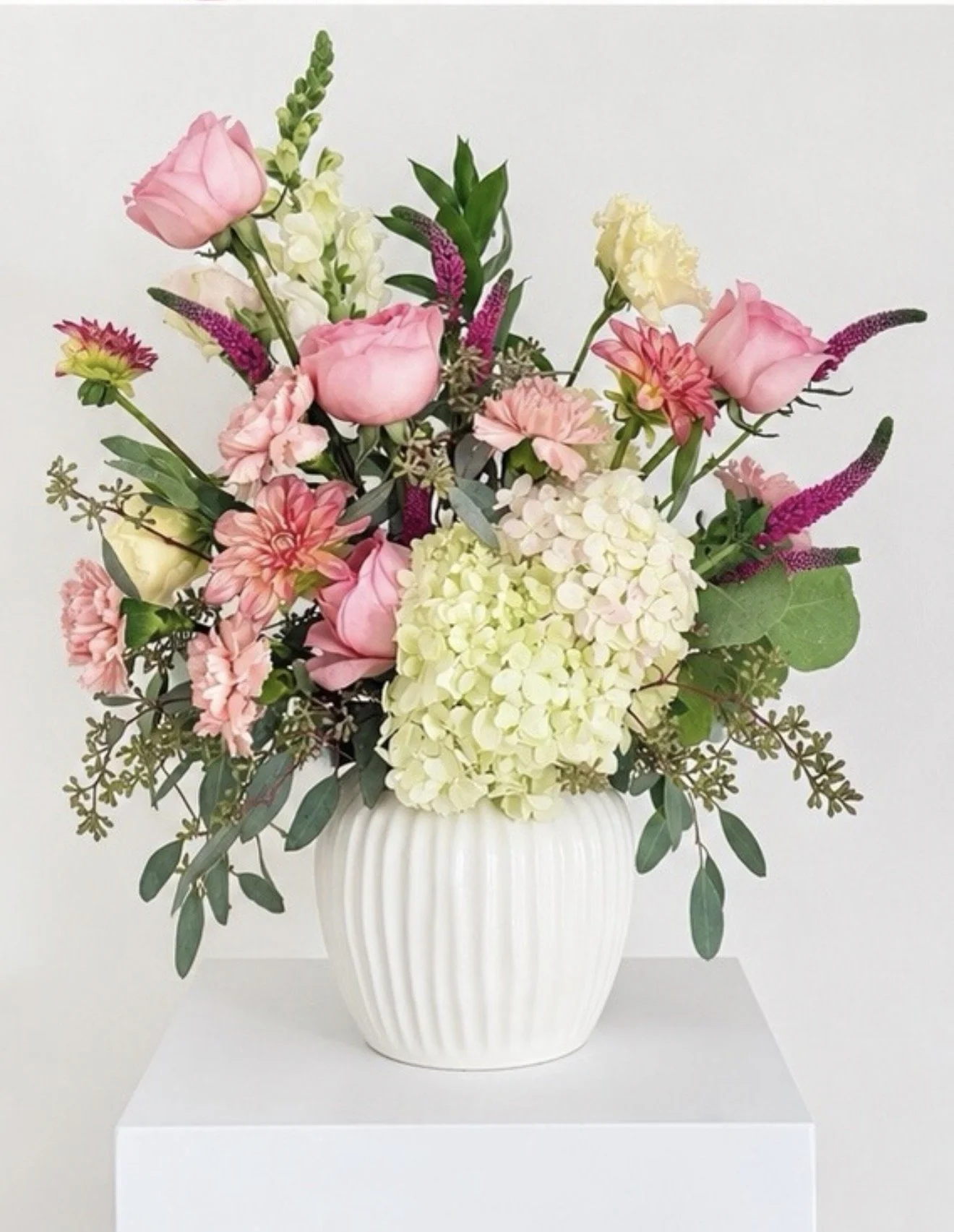 Pink rose and hydrangea floral arrangement with chrysanthemums and greenery in a white ribbed vase