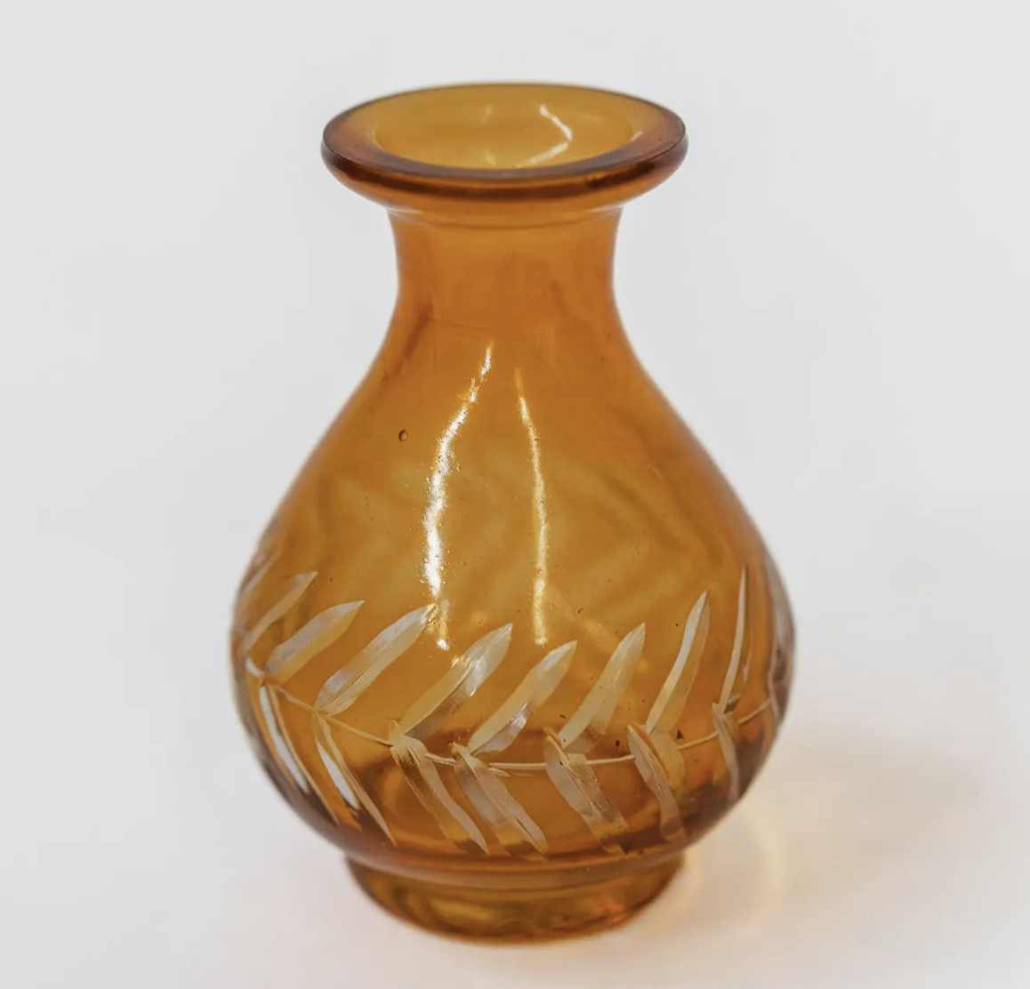 A small yellow glass vase featuring an elegant leaf design.