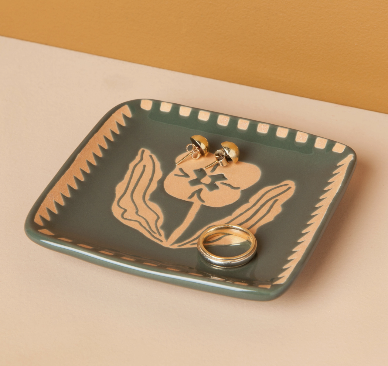 A green and gold tray featuring an intricate flower design, elegantly displayed for decorative purposes.