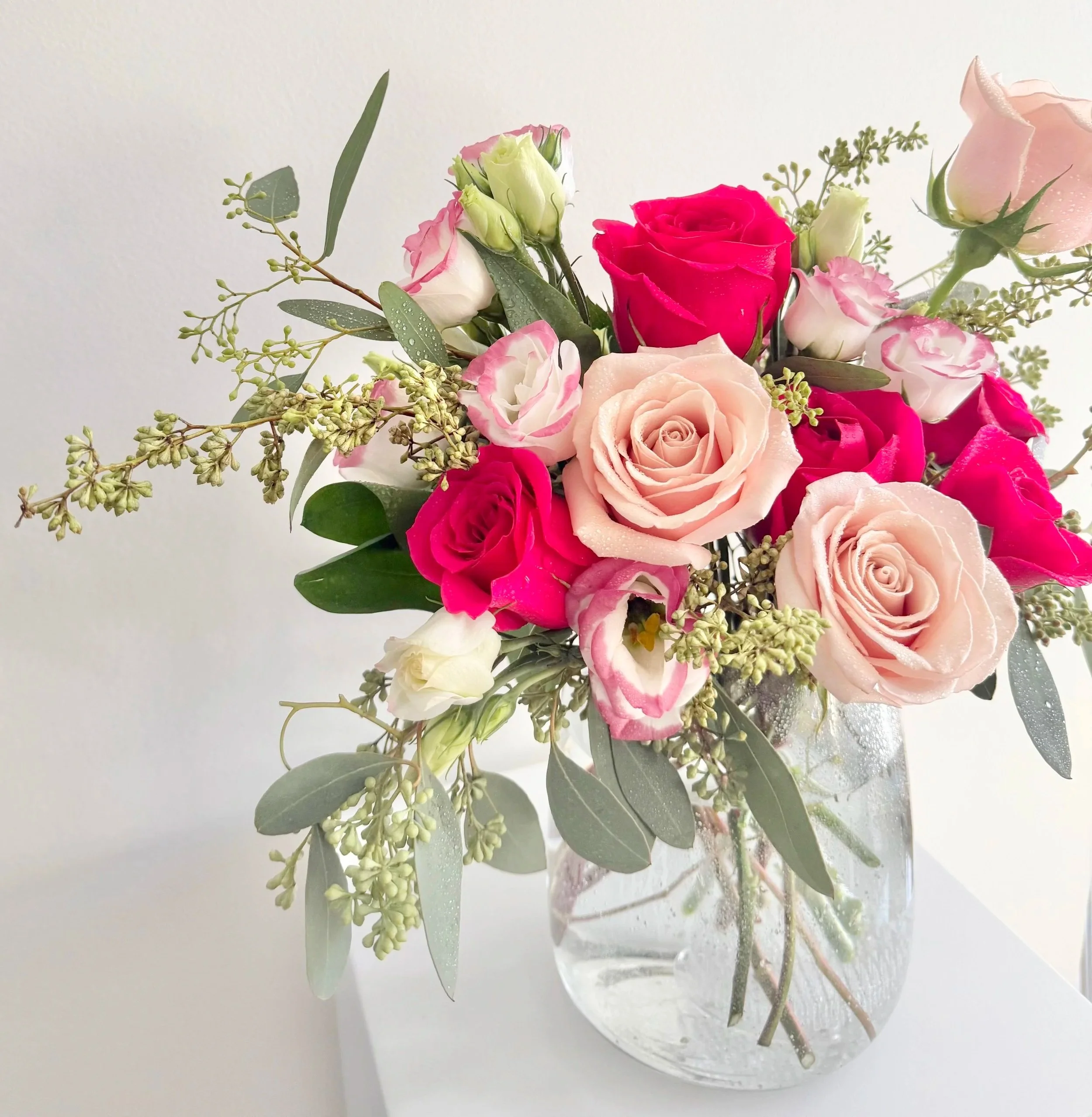 A decorative vase brimming with pink and red roses, highlighting their rich colors and natural beauty.