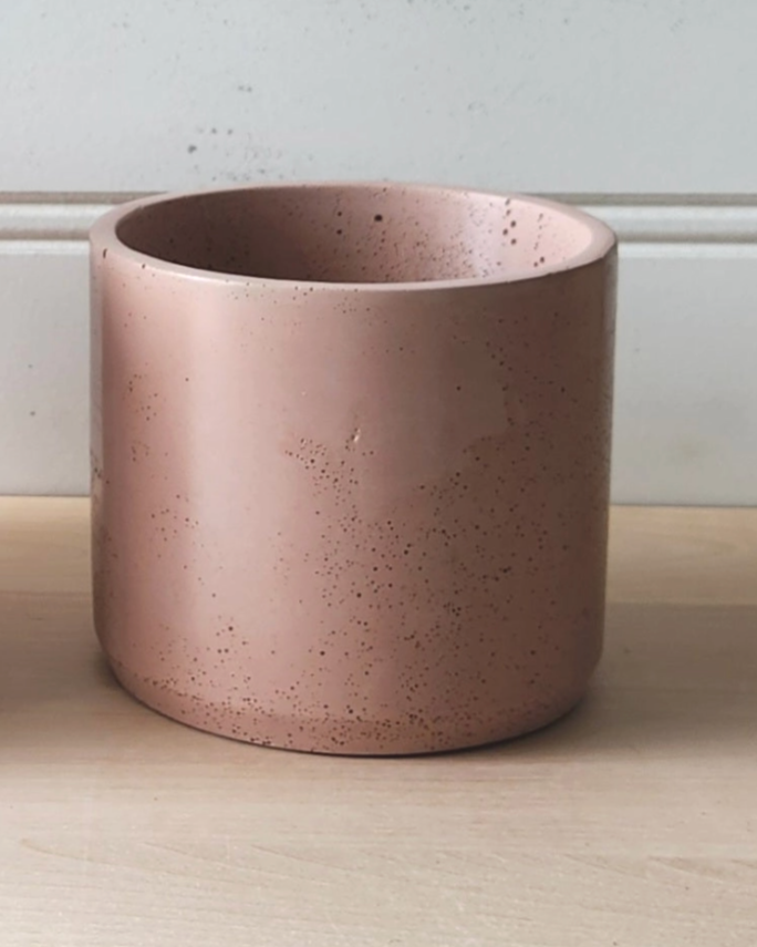 A pink ceramic cup placed on a wooden table, showcasing its smooth surface and vibrant color.
