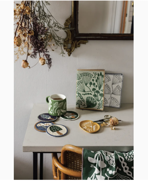 A table featuring a mirror, a cup, and a vase filled with colorful flowers, creating a charming and inviting scene.