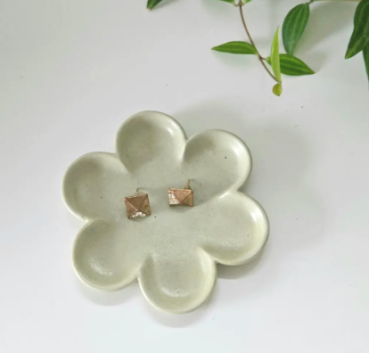 A flower-shaped plate featuring two small wooden studs at its center, designed for decorative or functional use.