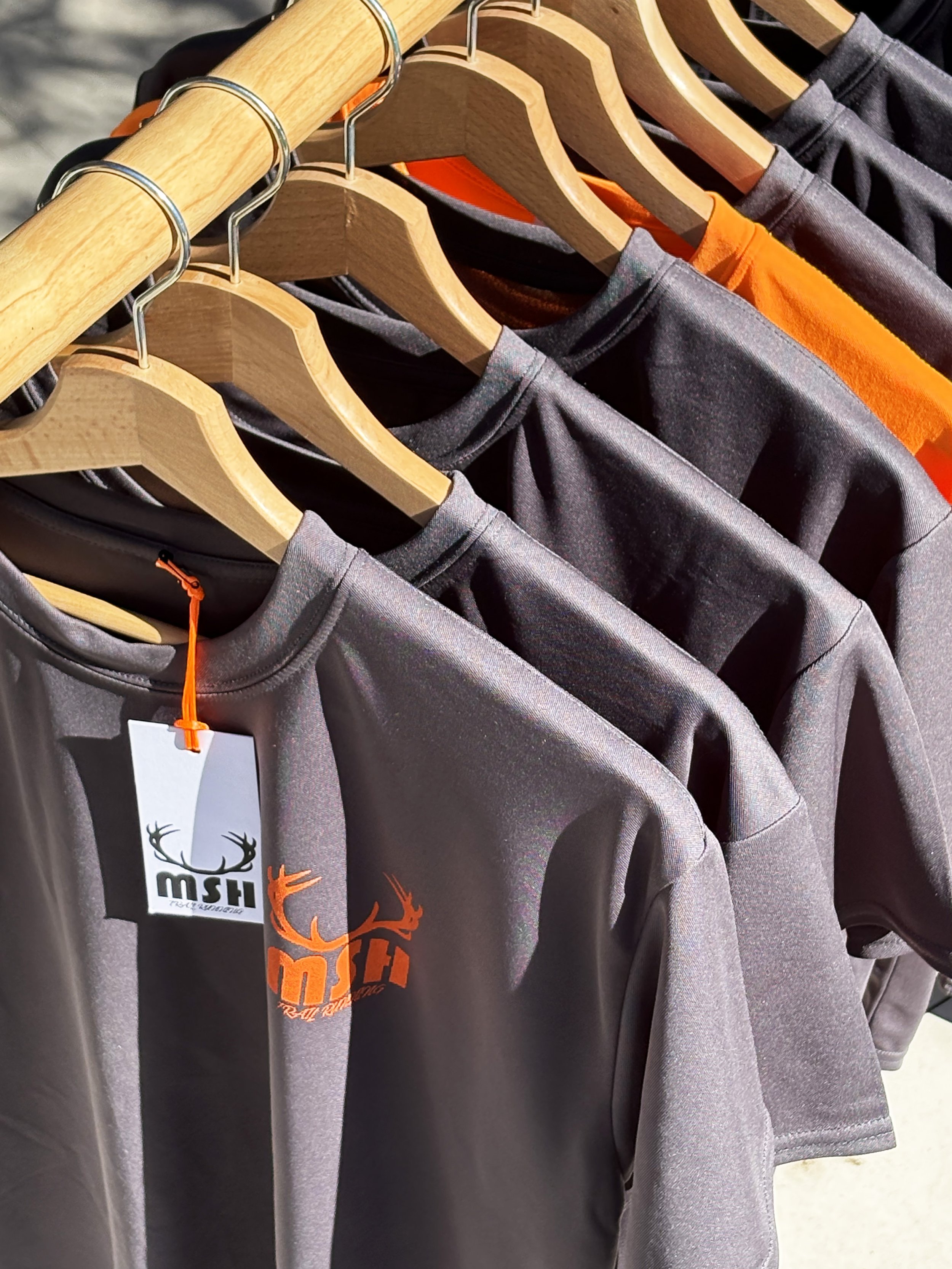 close up of a rack of grey and orange short sleeve t-shirts in an outdoor setting