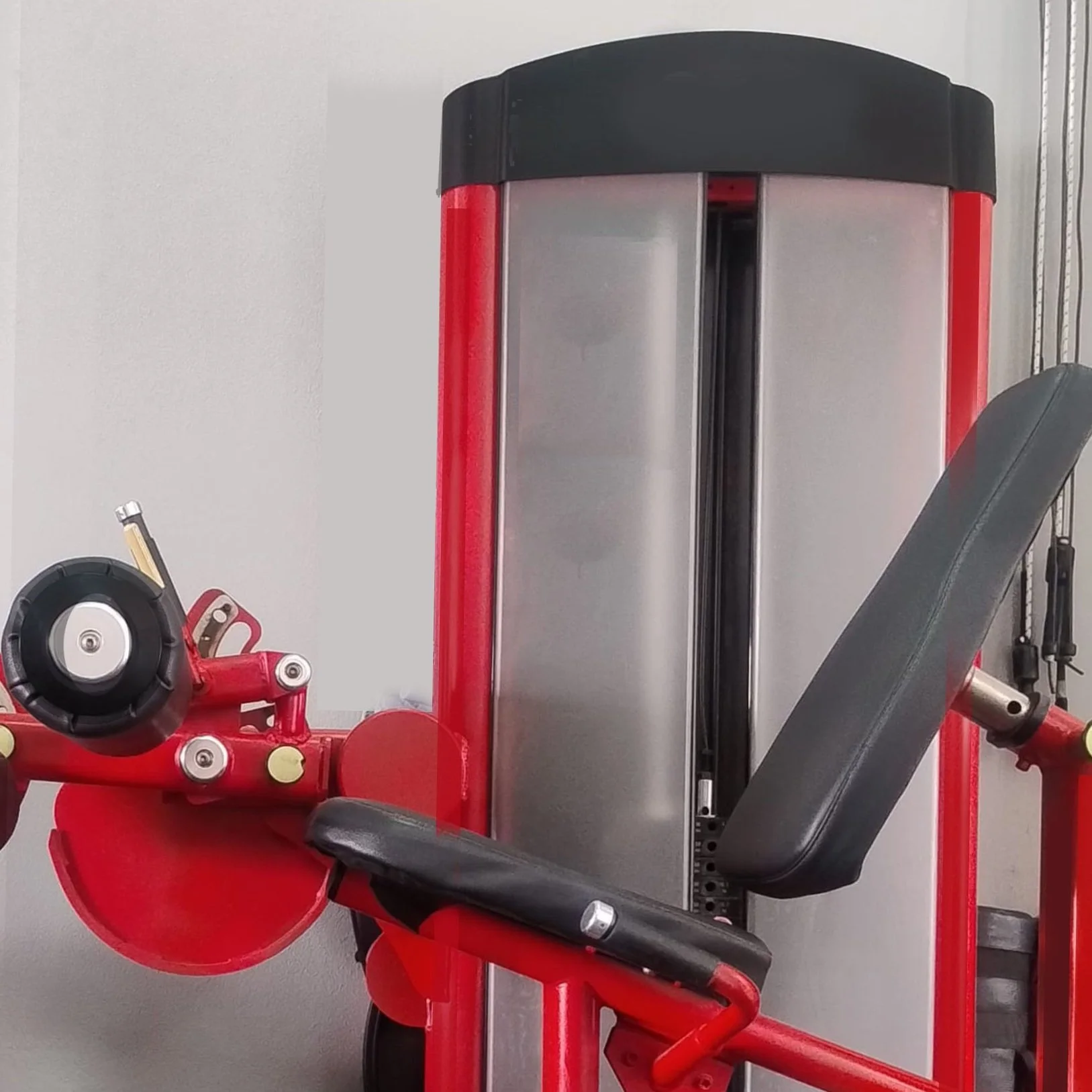 Máquina de ejercicios de gimnasio color rojo con asiento y peso de contrapeso.