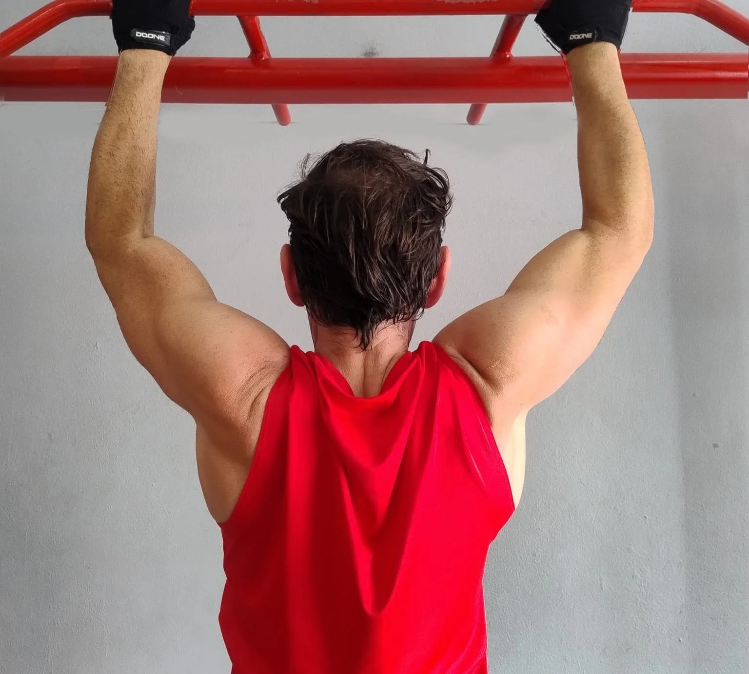 Hombre haciendo dominadas en una barra de ejercicio