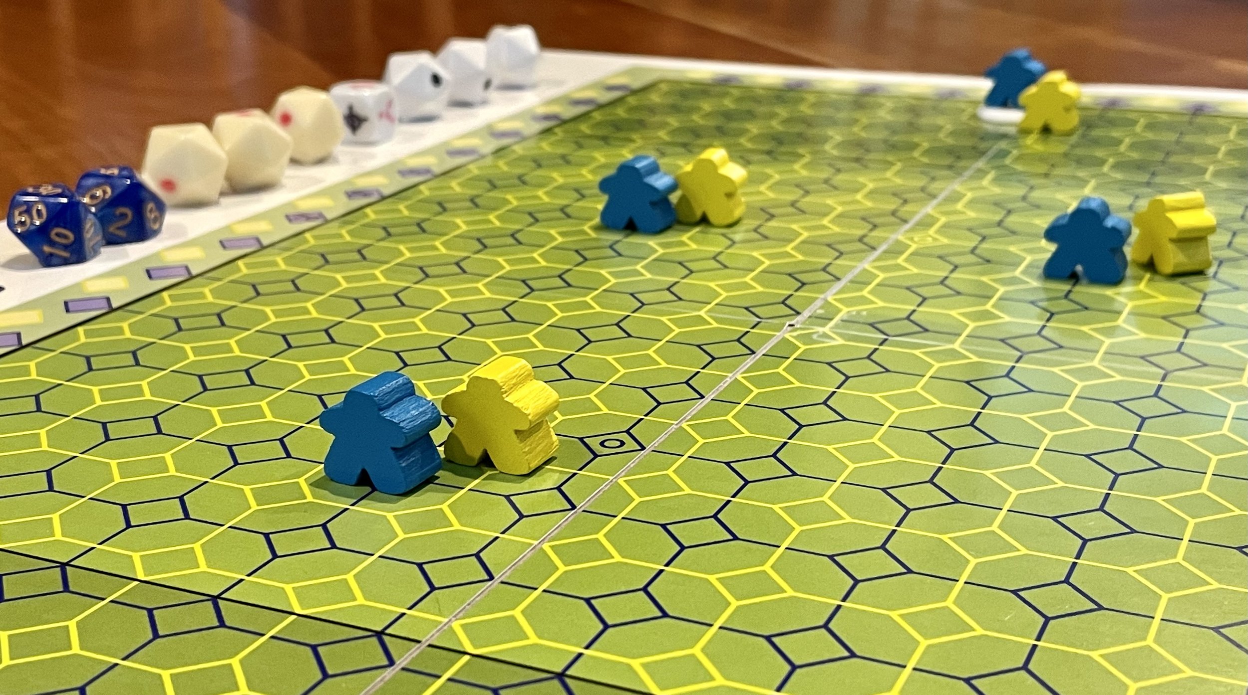 Board game with hexagonal pattern, yellow and blue meeples, dice lined up.