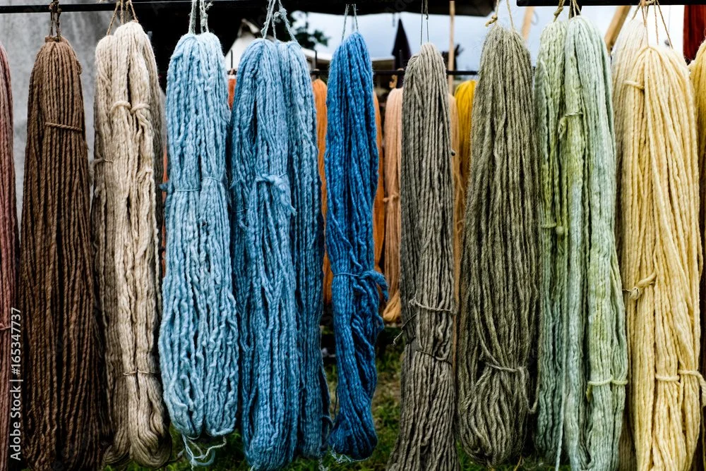 Colorful bundles of yarn hanging on a rack at an outdoor market.
