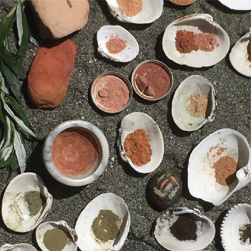 Various shells and stones with different powders and pigments inside, arranged on a dark surface.