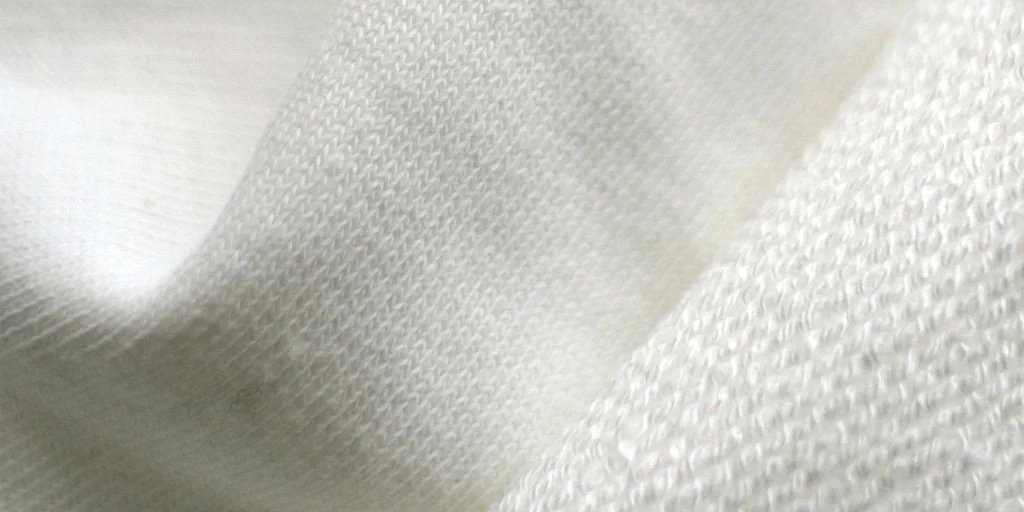 Close-up of off-white fabric with a textured pattern.