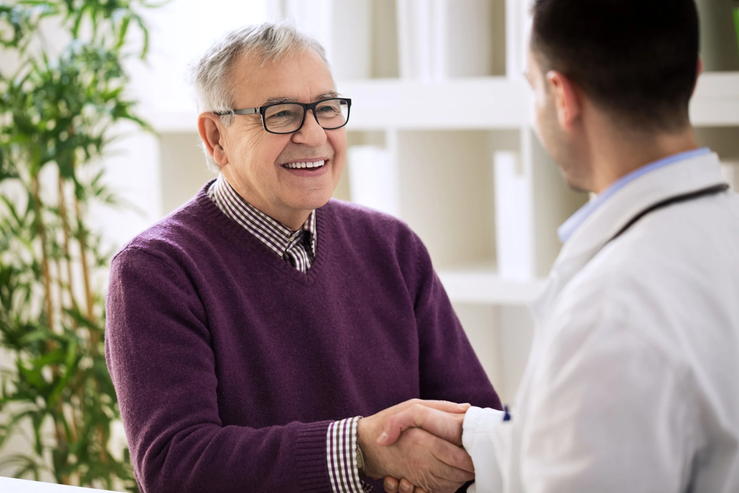 Old man smiles as he shakes hands with a doctor