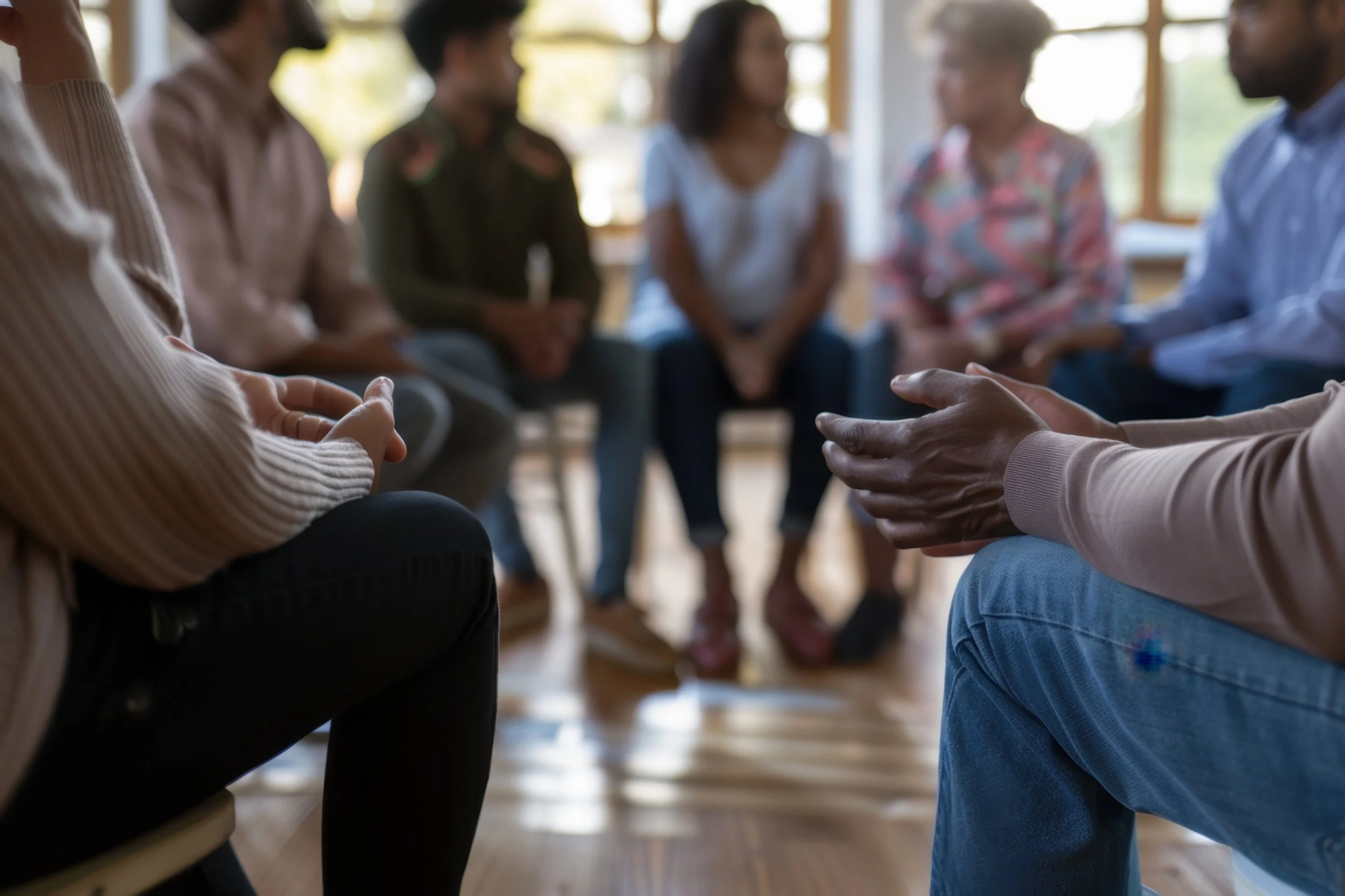 Close up of hands and legs as people sit in a circle sharing with each other