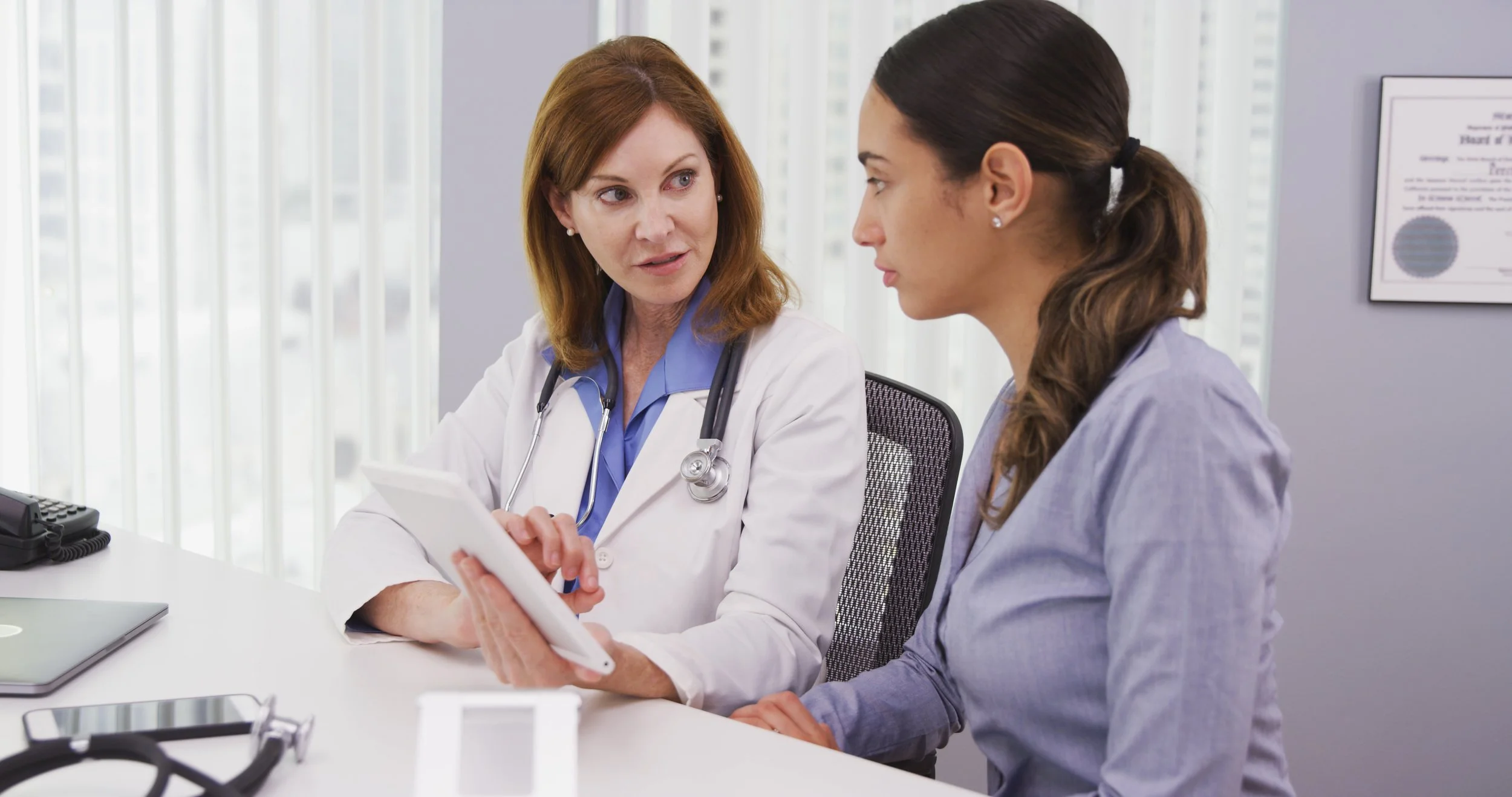 Doctor meets with patient, using a tablet to explain the patient's health condition and needs.