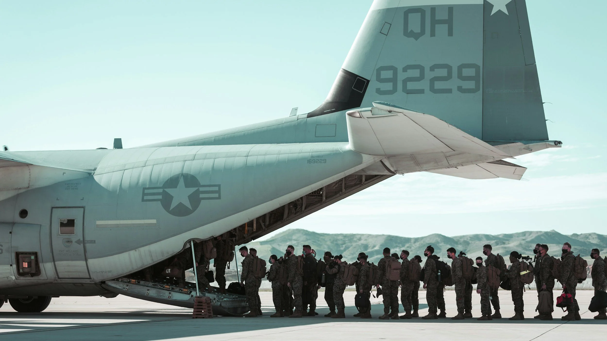 Military personnel boarding a cargo plane on a tarmac.