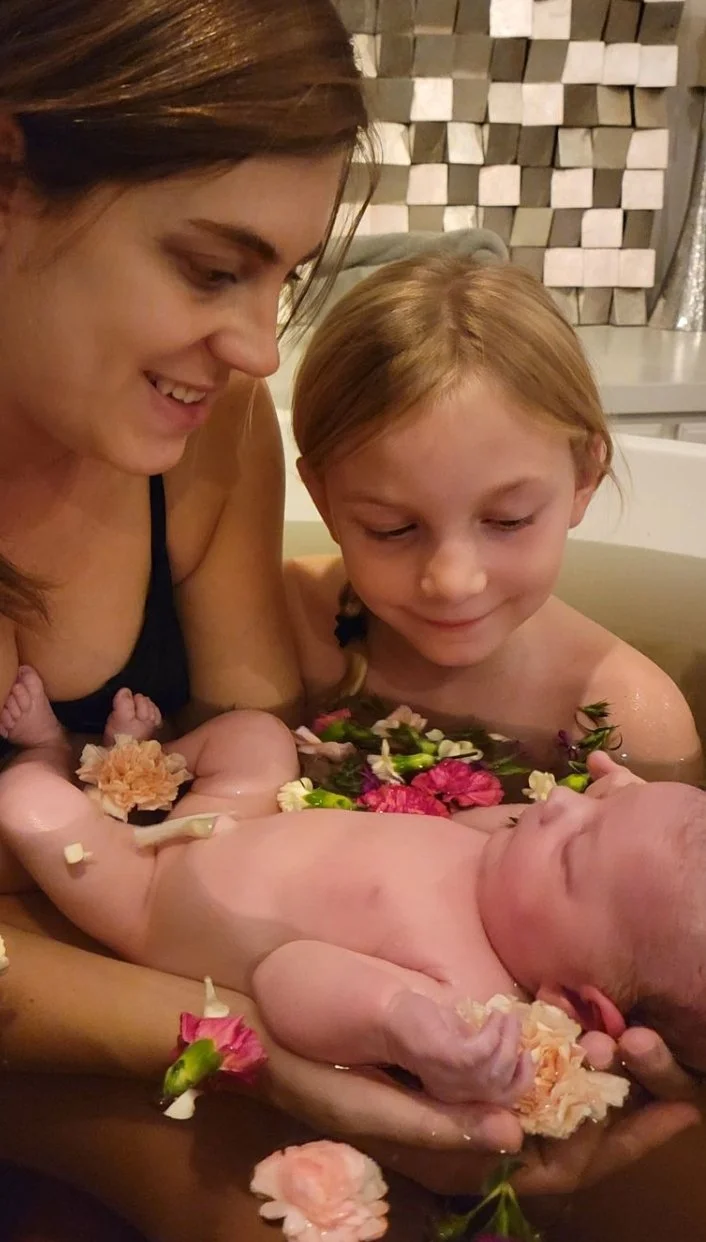 mom, baby, and big sister bonding in the organic herbal bath at the Center for Birth