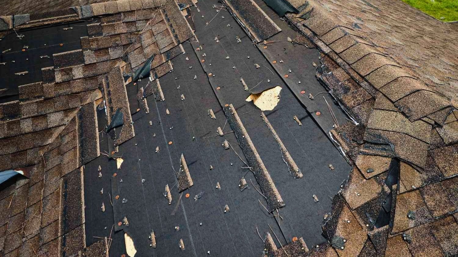 Exposed roof decking with missing shingles after hail storm