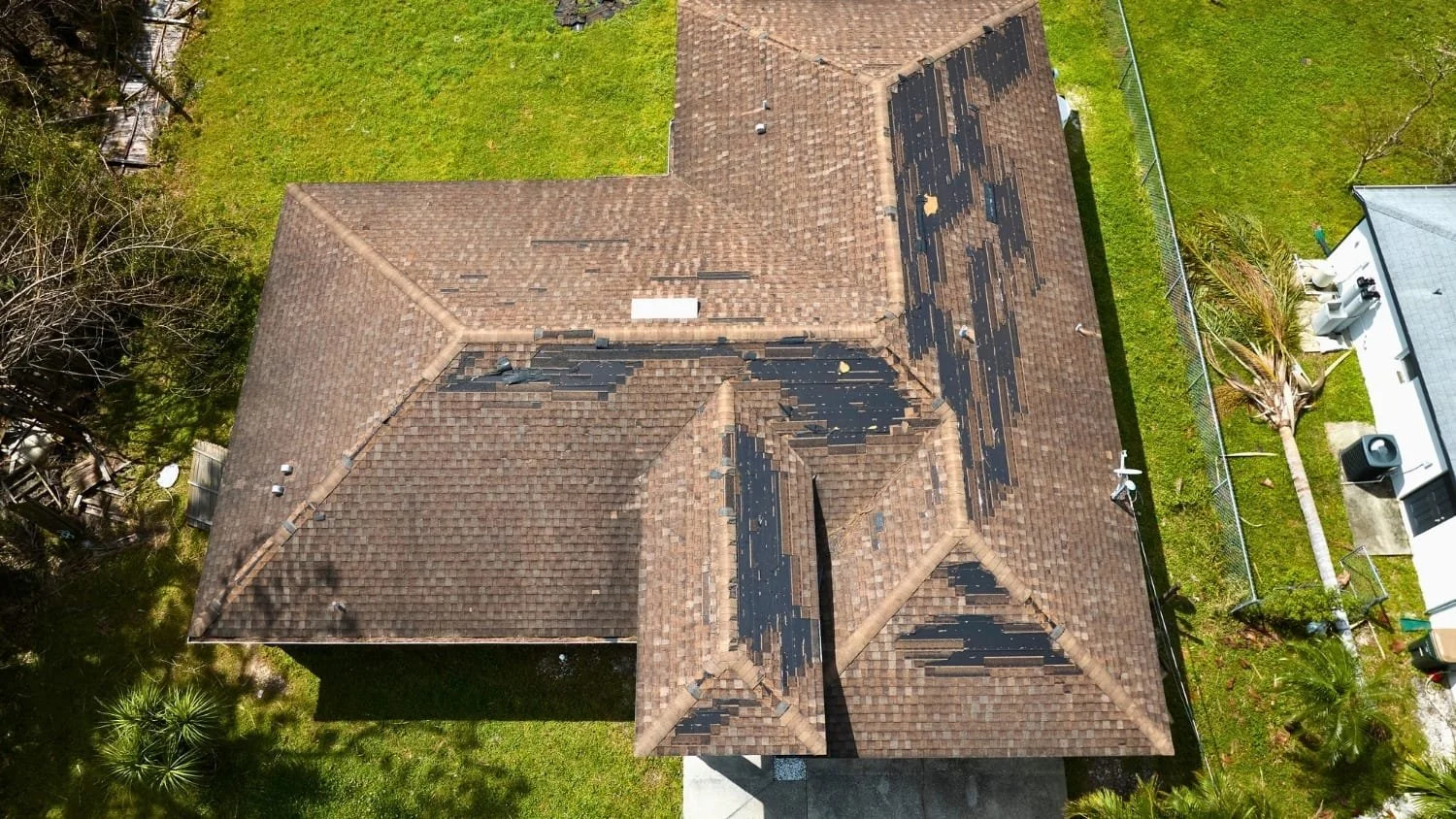 Damaged house roof with missing shingles after storm
