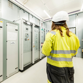 Battery storage engineer inspecting BESS control cabinets inside a UK energy storage facility.