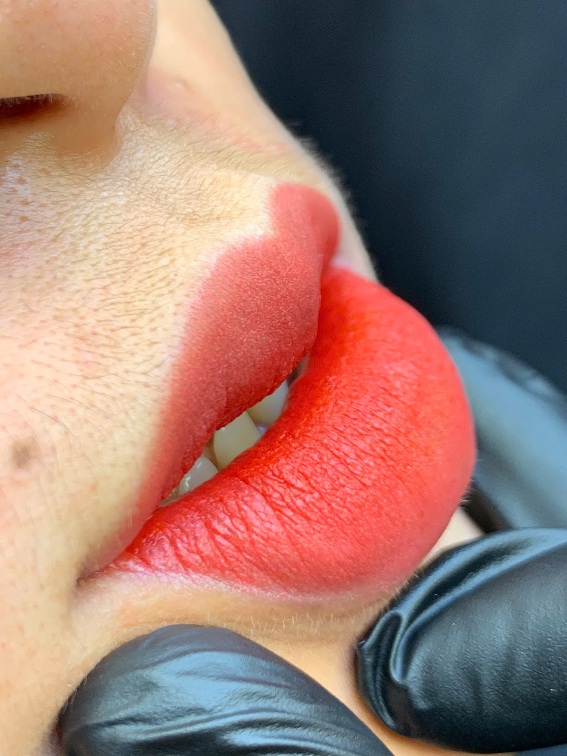 Close-up of lips with red lipstick and gloved hands