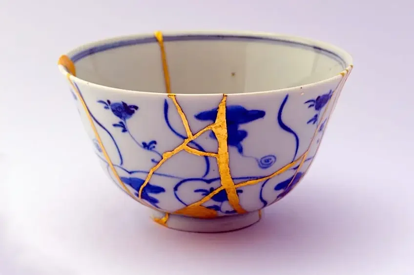 A damaged porcelain bowl with blue floral patterns, showing extensive gold-colored cracks.