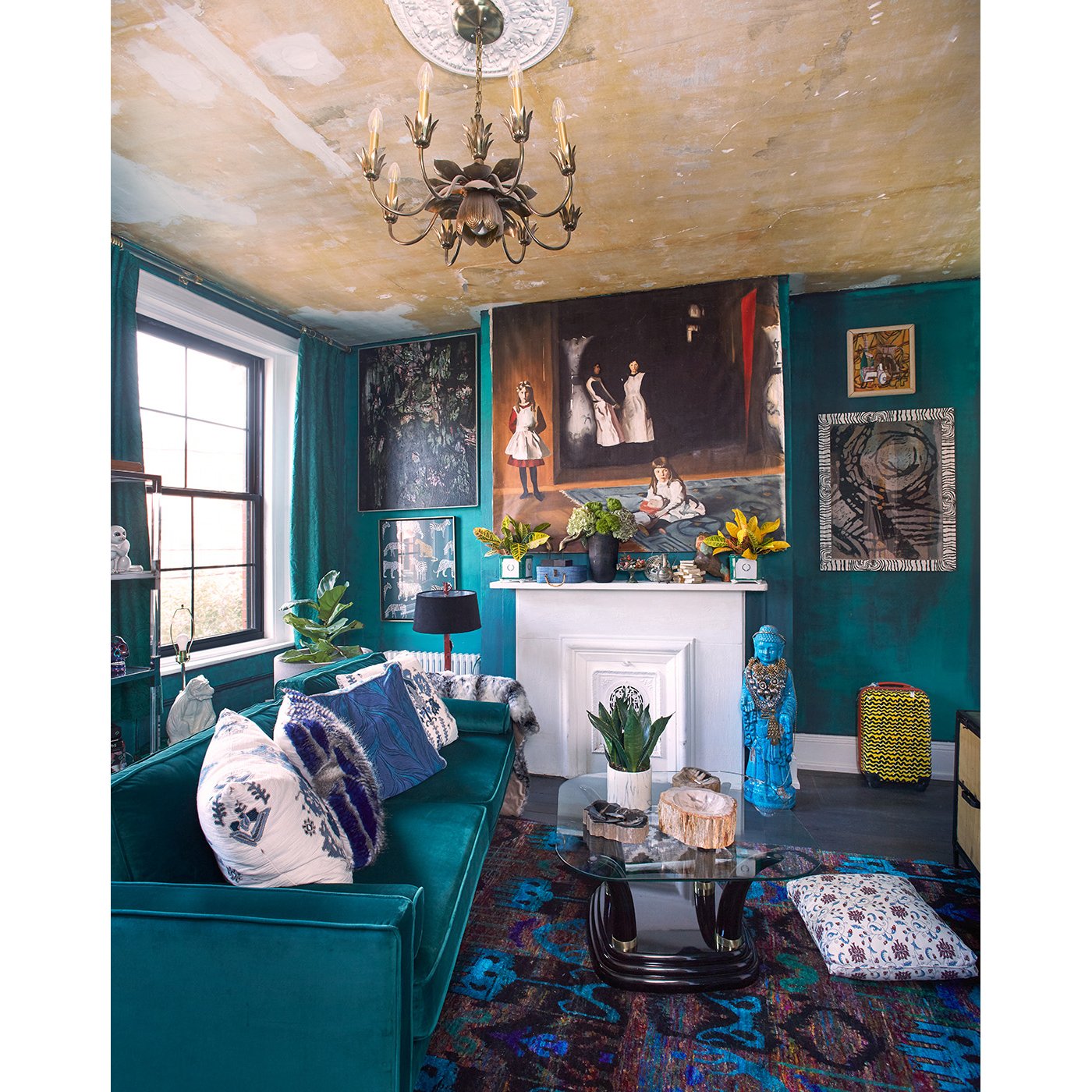 Eclectic living room with teal walls, velvet couch, colorful accent pillows, vibrant artwork, and a glass coffee table topped with decorative items. Residential Design, Renovation, Restoration, Interior Design and Decor, Art Curation Hope Misterek