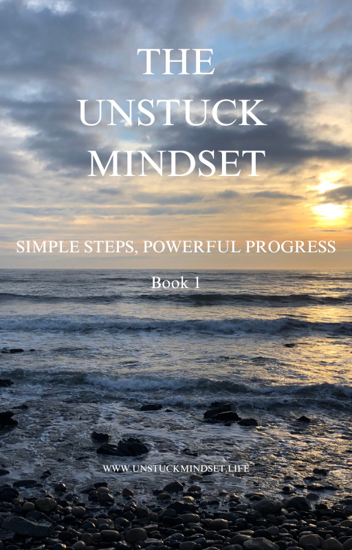 Book cover titled "The Unstuck Mindset" featuring a sunset over the ocean with rocks and waves in the foreground.