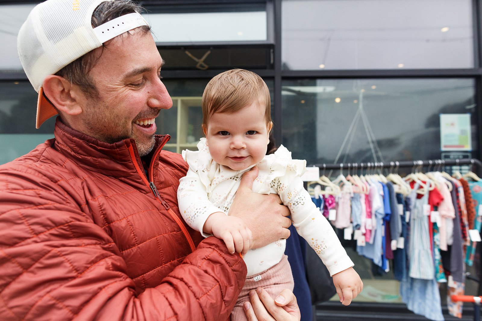 A man lifting a young boy in the air, both are smiling and playing together indoors against a plain wall.